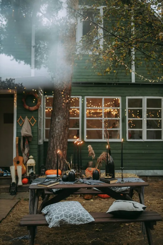 Rustic outdoor autumn decor with pumpkins and fairy lights creating a cozy atmosphere.